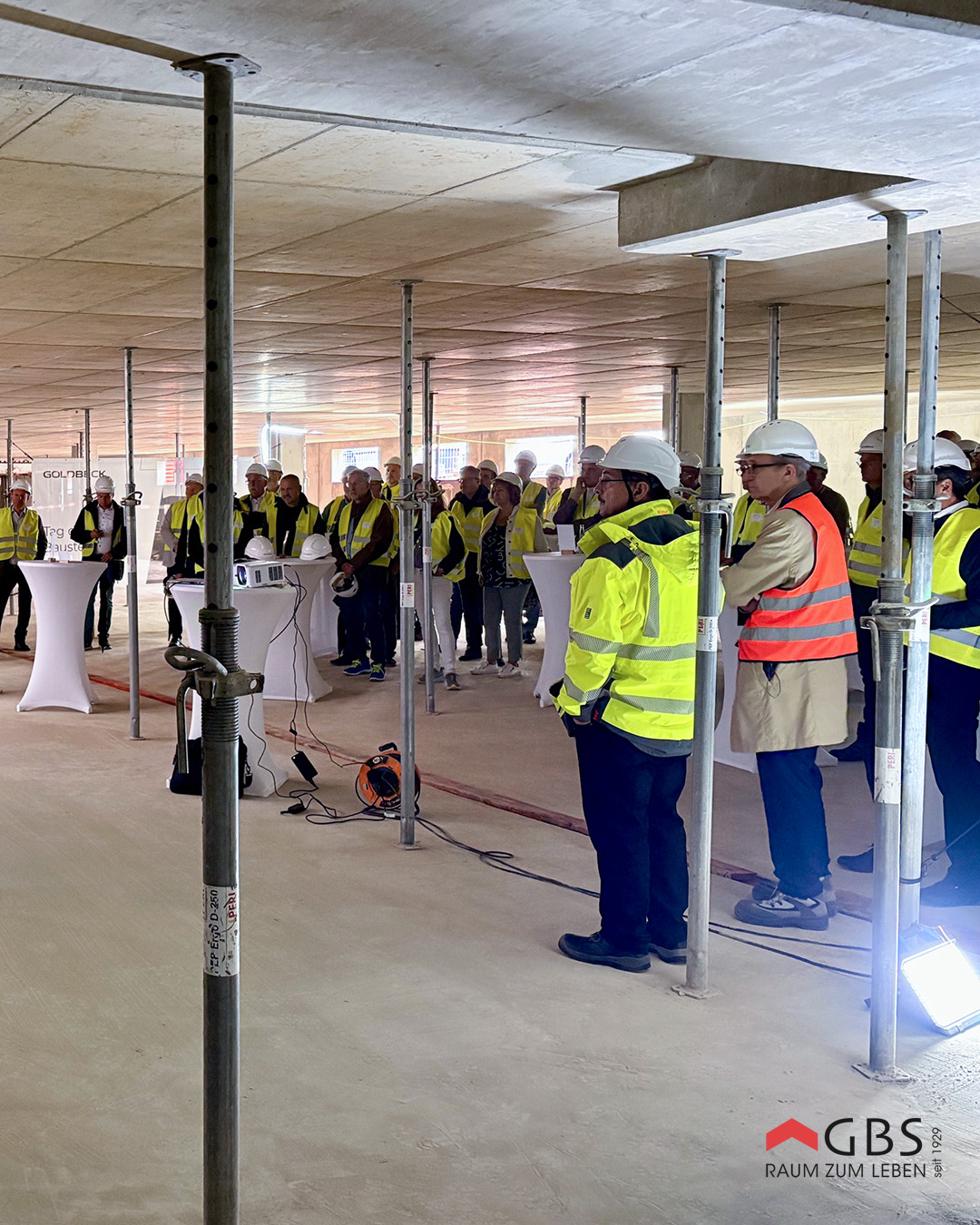 Teilnehmende verfolgen die Projektvorstellung im Rohbau im Husarenweg.