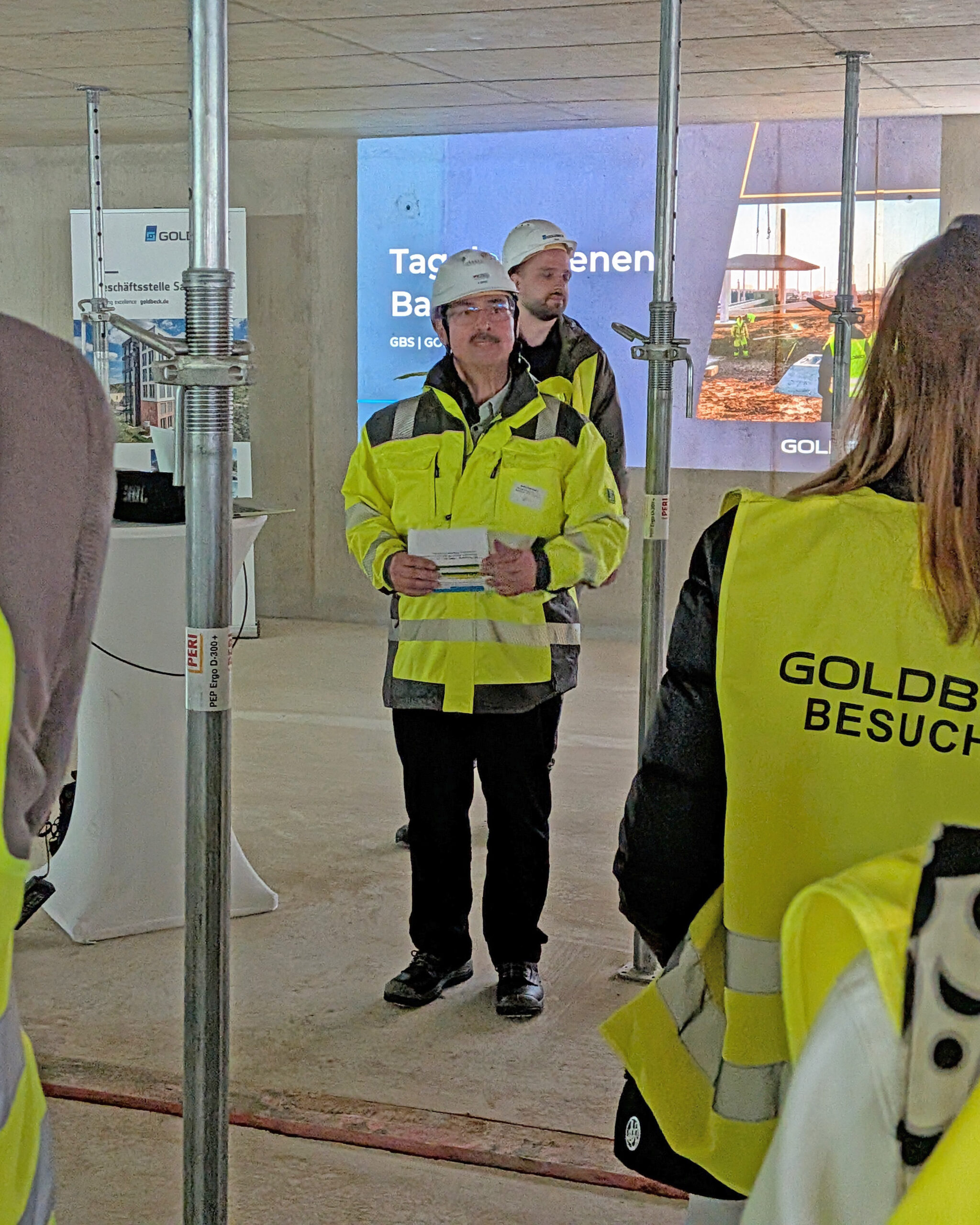 Begrüßung und Projektvorstellung vor der Präsentationswand im Rohbau im Husarenweg.